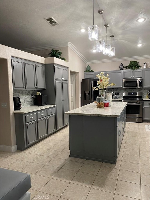 kitchen with gray cabinets, appliances with stainless steel finishes, tasteful backsplash, decorative light fixtures, and a kitchen island