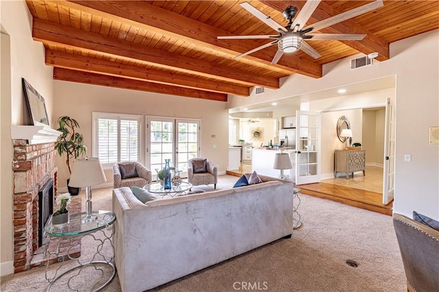 carpeted living room featuring ceiling fan, beam ceiling, wooden ceiling, and a fireplace