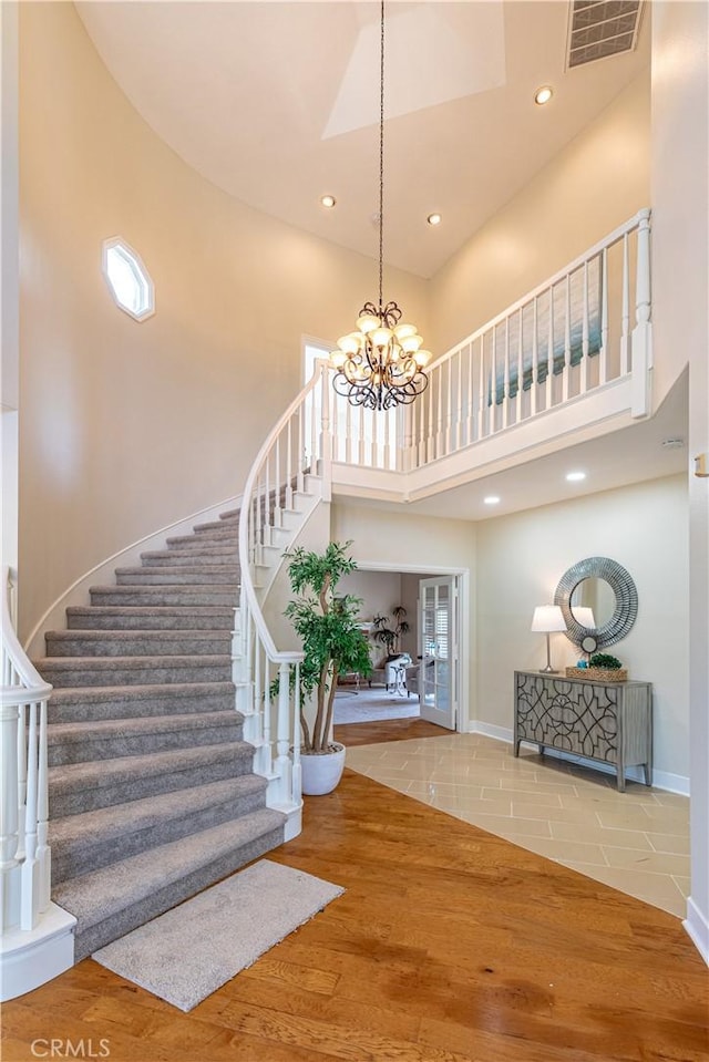 foyer featuring a notable chandelier, wood-type flooring, and a towering ceiling