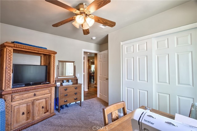 bedroom featuring dark colored carpet, ceiling fan, and a closet