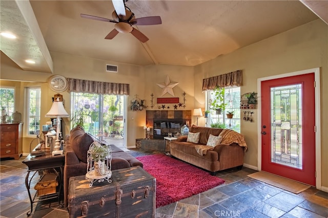 living room featuring ceiling fan and a tiled fireplace