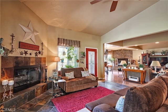 living room featuring ceiling fan, a fireplace, and high vaulted ceiling