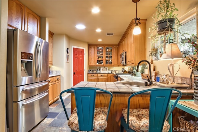 kitchen featuring decorative light fixtures, sink, kitchen peninsula, and stainless steel appliances