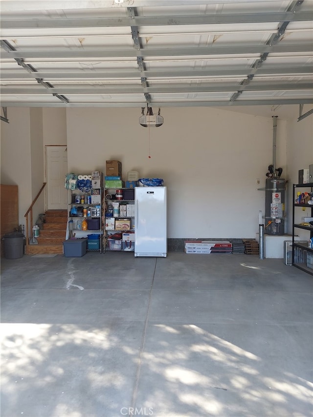 garage with water heater, white fridge, and a garage door opener