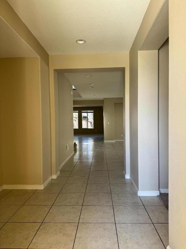 corridor featuring tile patterned flooring and a textured ceiling