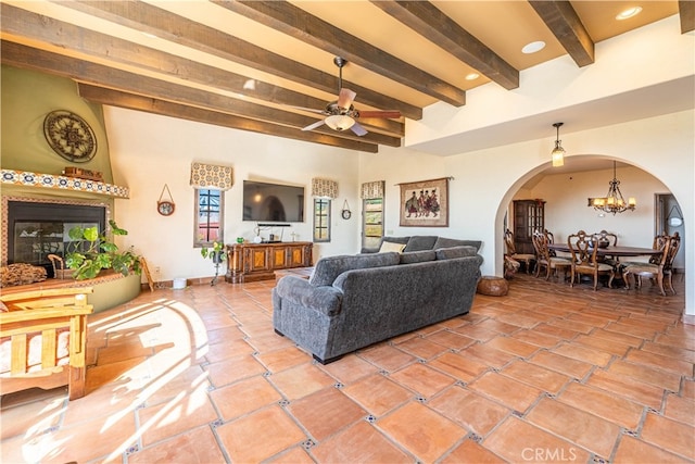 tiled living room with beamed ceiling and ceiling fan with notable chandelier