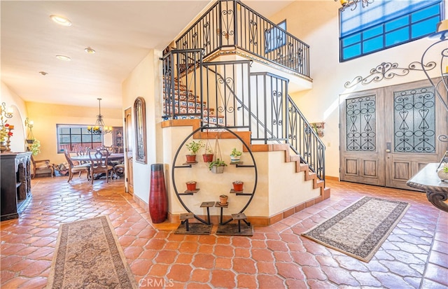 tiled foyer featuring french doors and an inviting chandelier