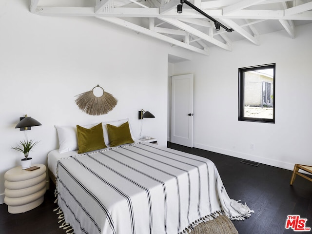 bedroom with beam ceiling and hardwood / wood-style floors