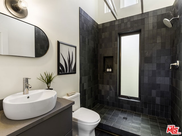 bathroom featuring tiled shower, vanity, and toilet