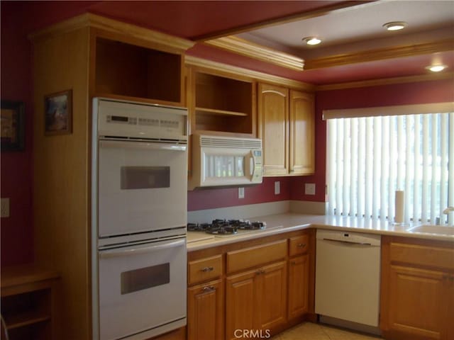 kitchen with white appliances, a raised ceiling, crown molding, sink, and light tile patterned flooring