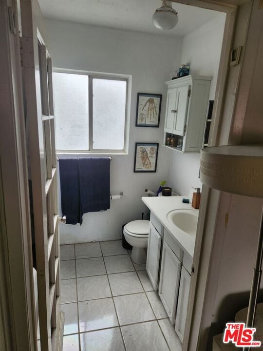 bathroom with tile flooring, vanity, and toilet