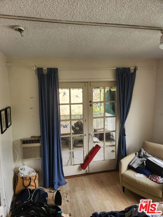 bedroom with wood-type flooring, french doors, and a textured ceiling