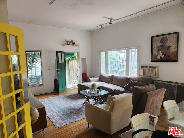 living room with an AC wall unit, rail lighting, and hardwood / wood-style floors