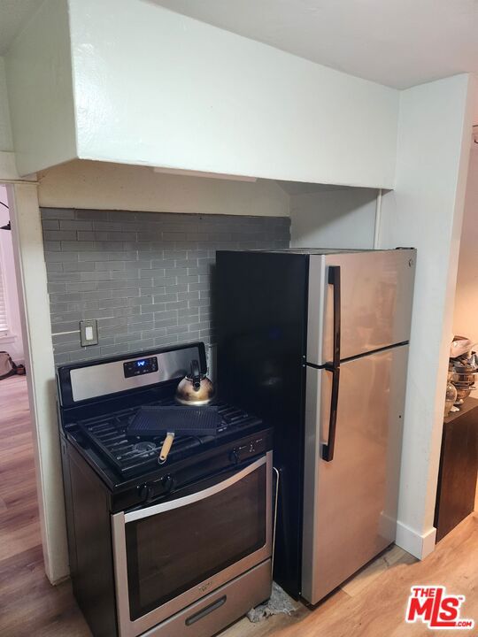 kitchen featuring appliances with stainless steel finishes, hardwood / wood-style flooring, and backsplash