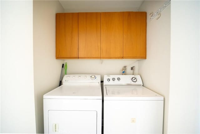 clothes washing area with washer and clothes dryer and cabinets