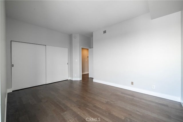 unfurnished bedroom with dark hardwood / wood-style flooring and a closet