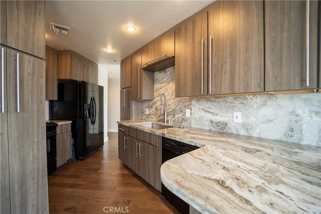 kitchen with sink, light stone counters, dark hardwood / wood-style floors, backsplash, and black appliances