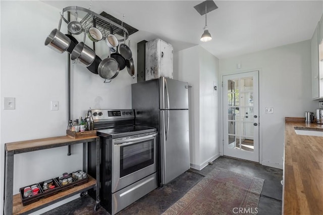 kitchen featuring butcher block countertops, decorative light fixtures, and appliances with stainless steel finishes