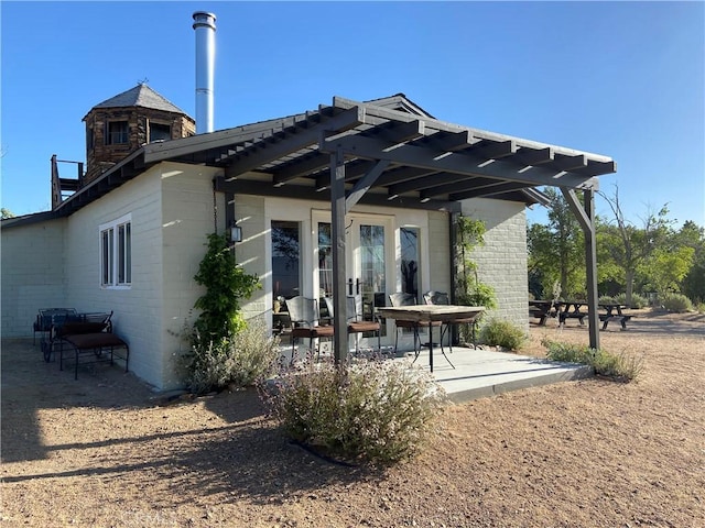 rear view of property featuring a pergola and a patio area