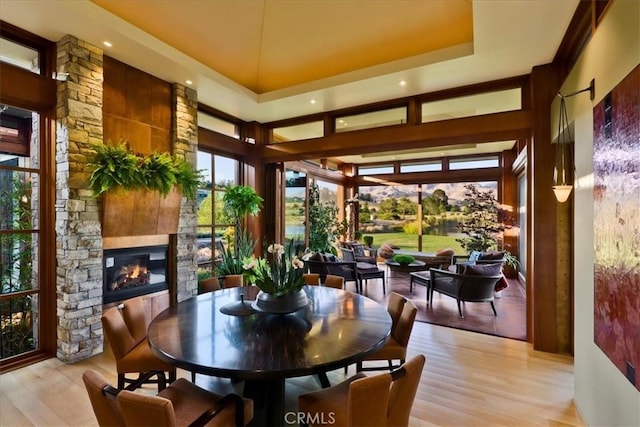 dining area with a raised ceiling, a fireplace, and light hardwood / wood-style flooring