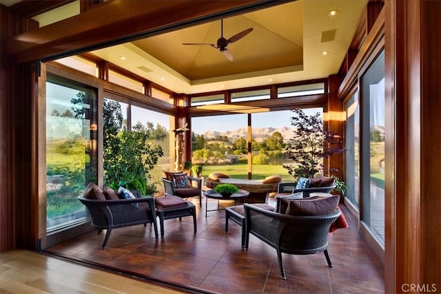 sunroom featuring ceiling fan, a mountain view, and a tray ceiling