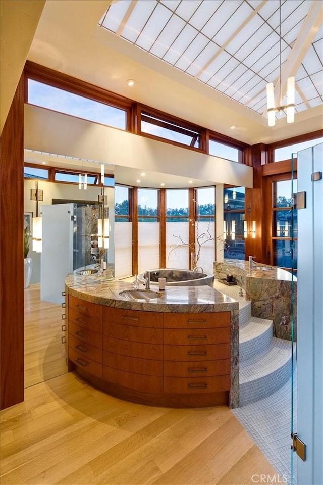 kitchen featuring a water view, sink, light wood-type flooring, a notable chandelier, and kitchen peninsula