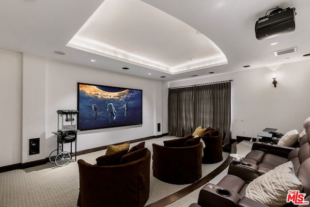 carpeted home theater room with a raised ceiling