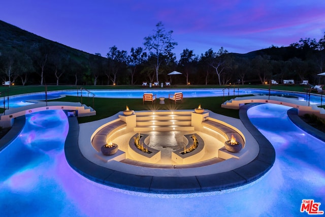 pool at dusk with a mountain view and a fire pit