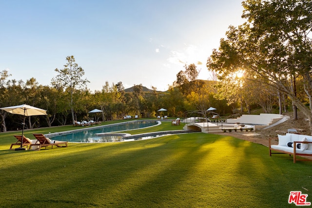 surrounding community featuring a swimming pool, a mountain view, and a lawn