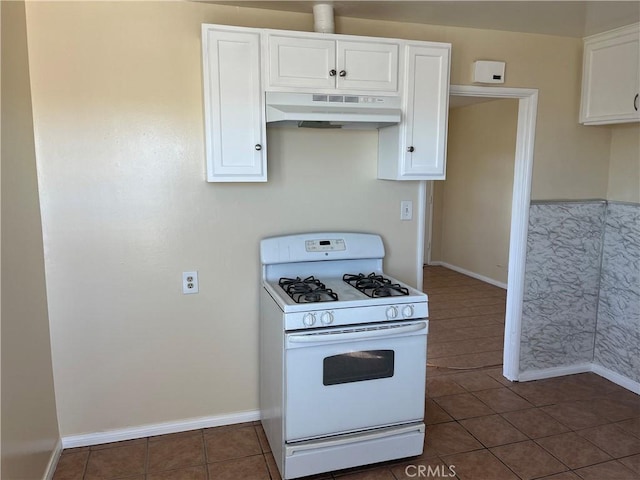 kitchen with dark tile patterned floors, white gas stove, and white cabinets