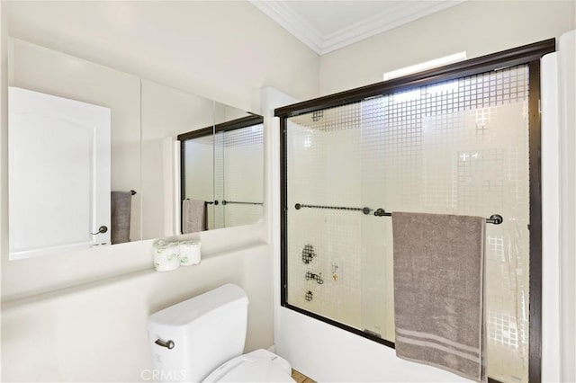 bathroom with toilet, crown molding, and bath / shower combo with glass door