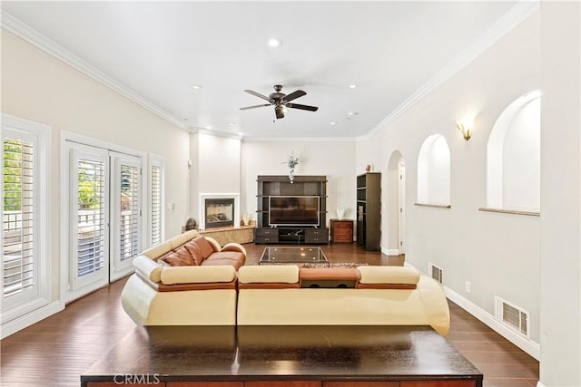 living room with dark hardwood / wood-style flooring, ceiling fan, and crown molding