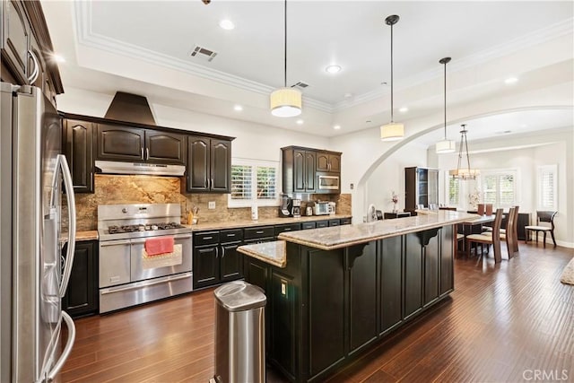 kitchen featuring stainless steel appliances, a kitchen island, hanging light fixtures, and a healthy amount of sunlight