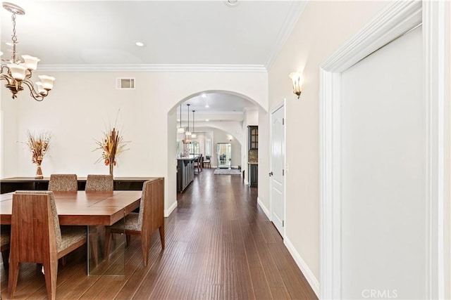 dining area featuring a notable chandelier, dark hardwood / wood-style flooring, and ornamental molding