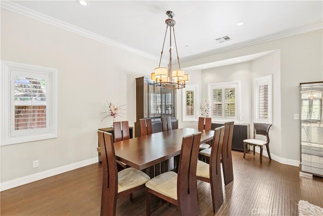 dining room with a healthy amount of sunlight, dark hardwood / wood-style flooring, ornamental molding, and an inviting chandelier