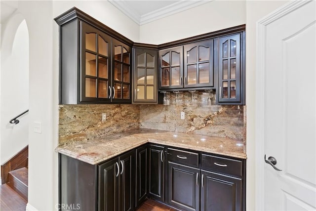 bar featuring decorative backsplash, wood-type flooring, light stone counters, and crown molding