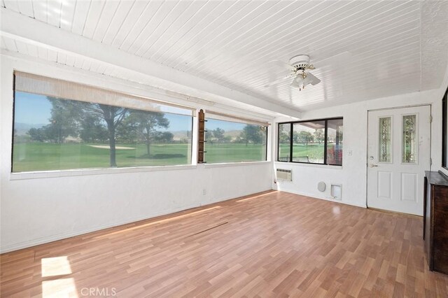 unfurnished sunroom with beamed ceiling, a wall mounted air conditioner, and ceiling fan