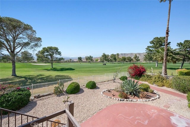 view of property's community featuring a mountain view, a yard, and a patio area