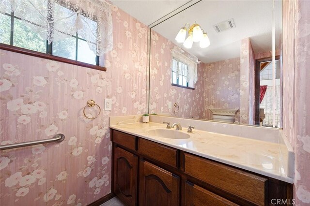 bathroom with a notable chandelier, toilet, and vanity