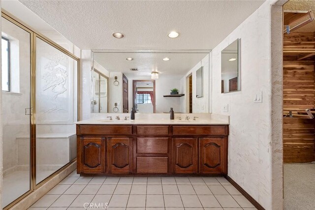 bathroom with a textured ceiling, an enclosed shower, and a healthy amount of sunlight