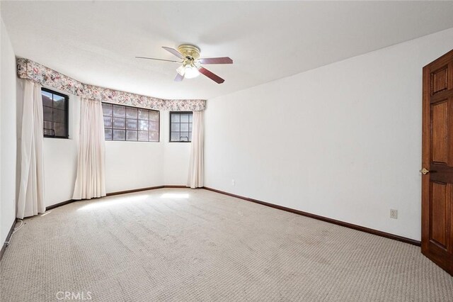 spare room with ceiling fan and light carpet