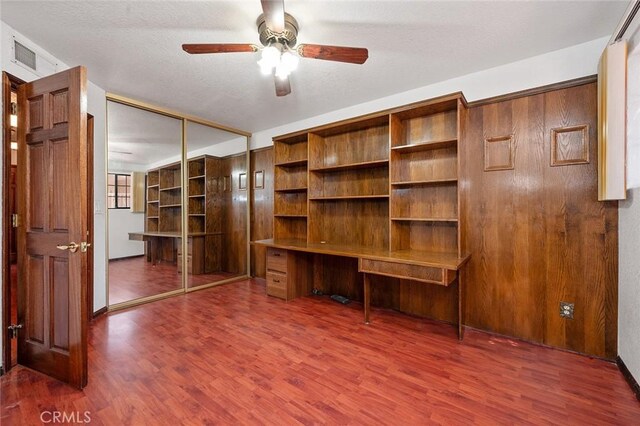 unfurnished office with ceiling fan and dark wood-type flooring