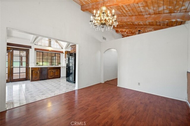 unfurnished living room featuring lofted ceiling with beams, light hardwood / wood-style flooring, wooden ceiling, and a notable chandelier