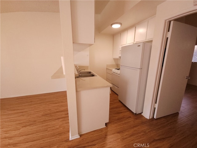 kitchen featuring white appliances, hardwood / wood-style flooring, and white cabinetry