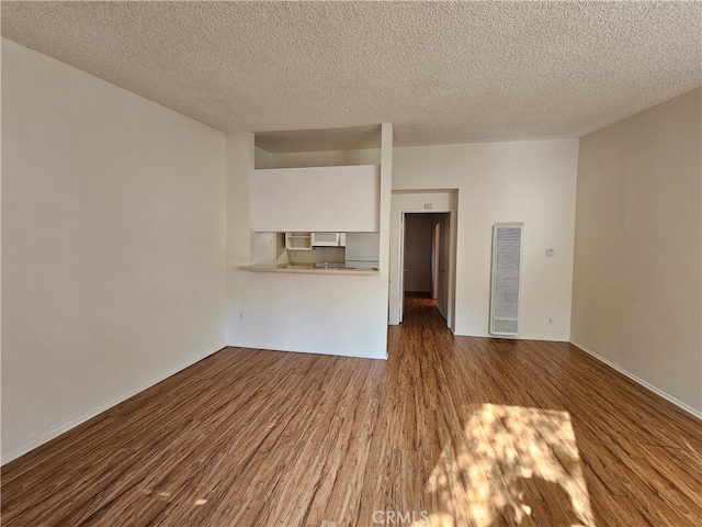 unfurnished living room with a textured ceiling and dark hardwood / wood-style flooring