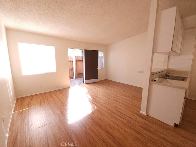 empty room featuring light hardwood / wood-style floors, a textured ceiling, and sink