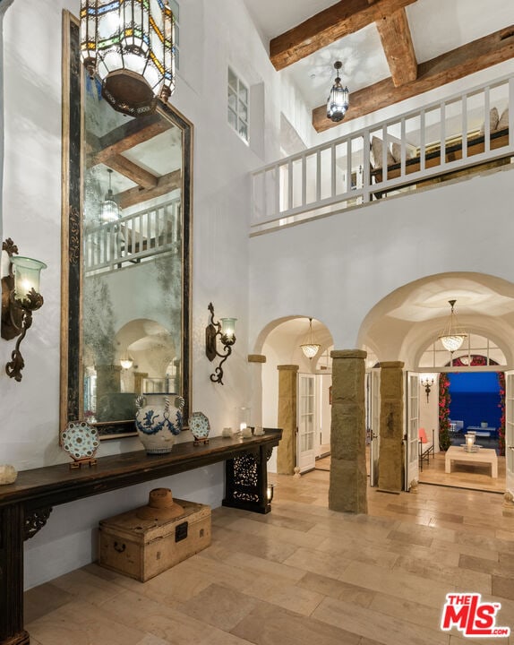 foyer featuring beamed ceiling, hardwood / wood-style flooring, and a high ceiling