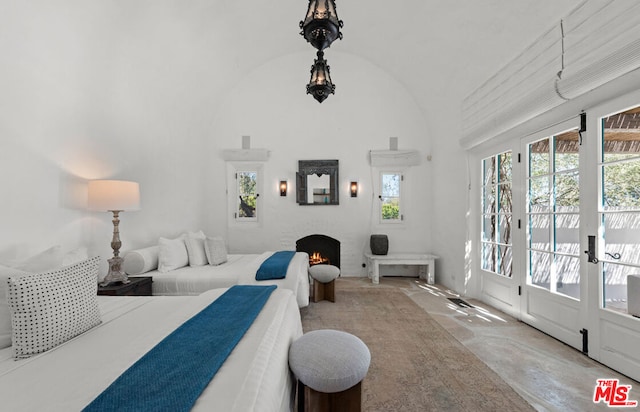 bedroom featuring high vaulted ceiling, concrete flooring, and access to outside