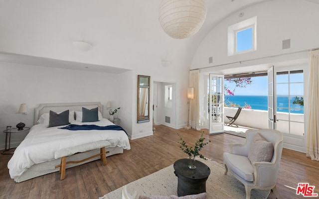 bedroom with high vaulted ceiling, multiple windows, a water view, and dark hardwood / wood-style floors