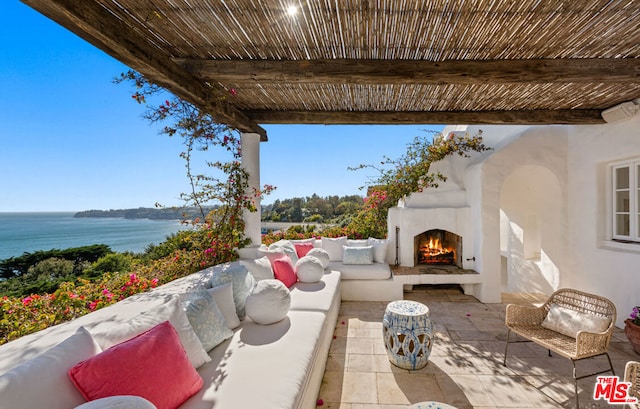 view of patio / terrace with an outdoor living space with a fireplace and a water view